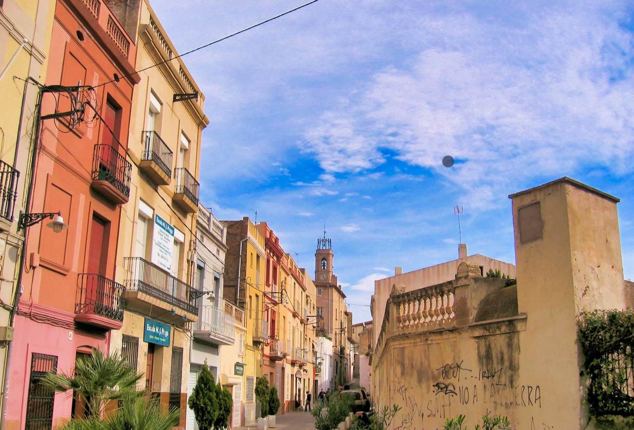 Calle de Dalt de la Vila con fachadas de colores y la torre de Santa Maria al fondo