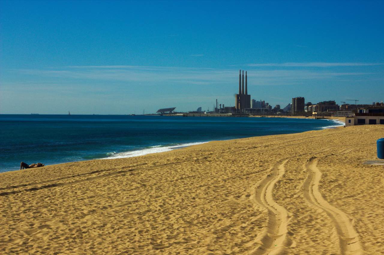 Vista del litoral de Badalona desde la arena, con el mar y la ciudad al fondo