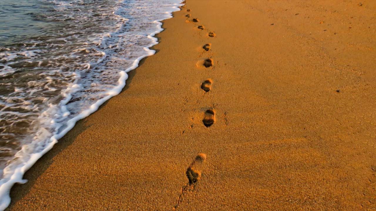 Orilla de una playa de Badalona con huellas sobre la arena junto al mar